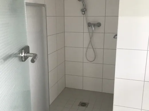 Bodengleiche Dusche im Dachgeschoss, gefliest, mit Glasabtrennung und Handbrause.